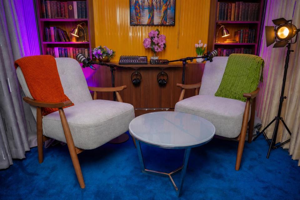 The Casa Media studio in Nairobi: two chairs and studio microphones set for a recorded conversation, framed by bookshelves and a lit backdrop.